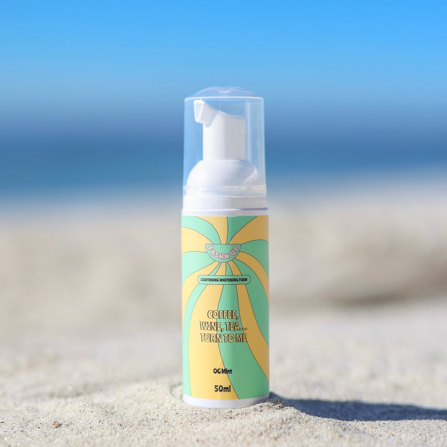Ultimate Lightening Whitening Vault sunscreen lotion by FRSHN UP on a sandy beach with a radiant smile in the background.