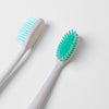 Two OG Toothbrushes with green and white bristles on a white surface by FRSHN UP.