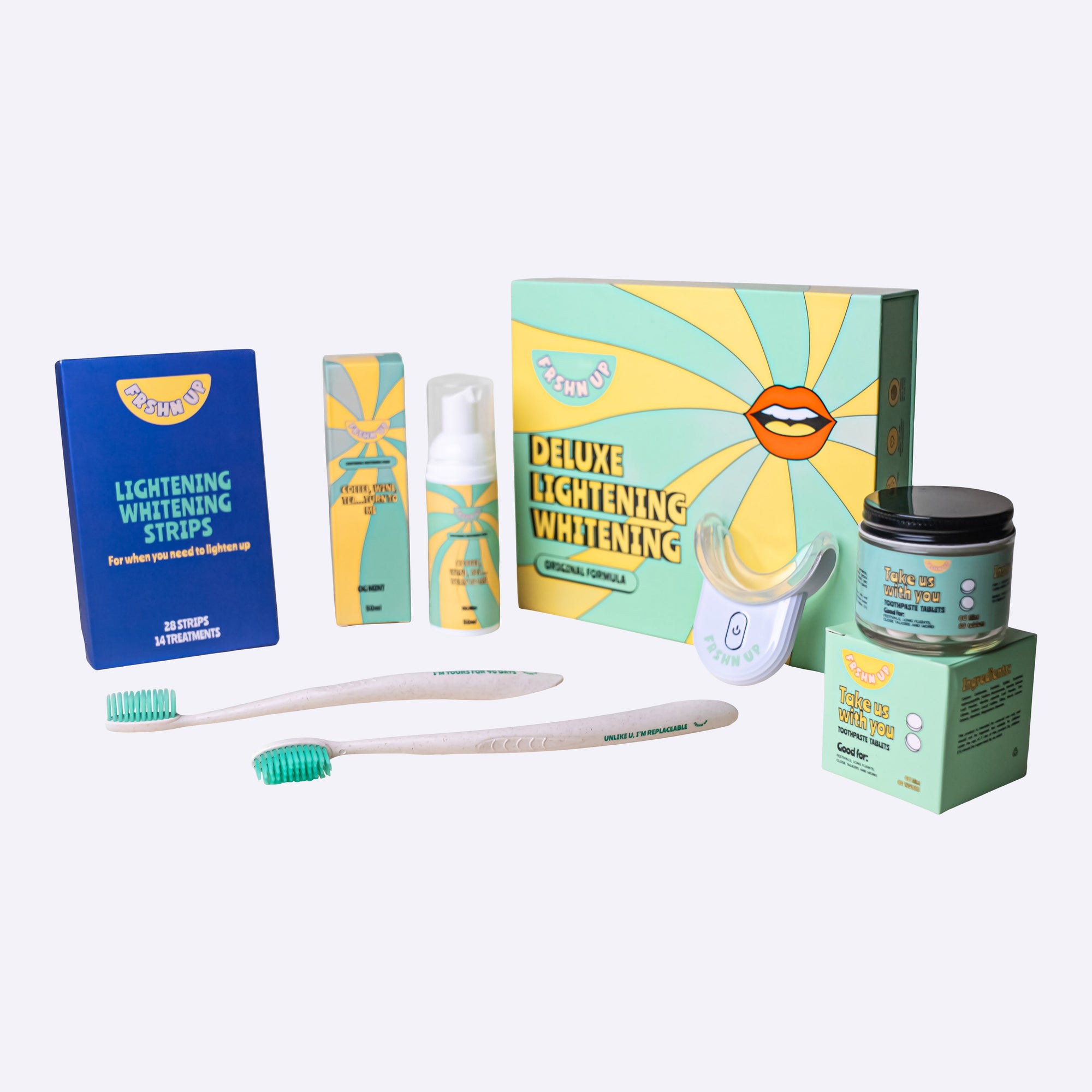 A comprehensive collection of FRSHN UP Ultimate Lightening Whitening Vault items, including a toothbrush and toothpaste, are displayed on a table.