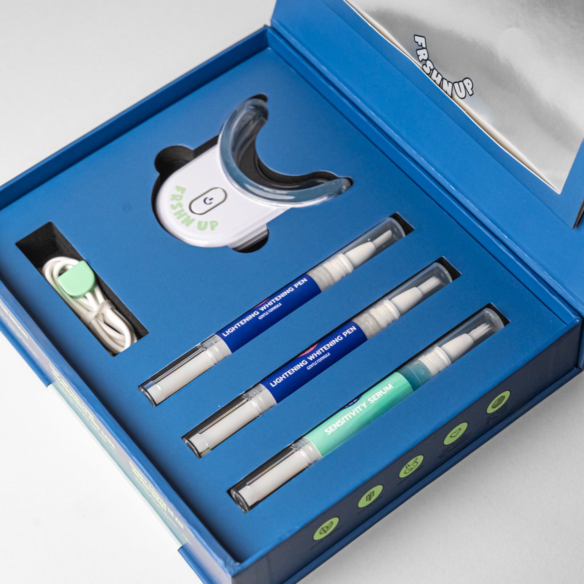 A blue box containing FRSHN UP Deluxe Lightening Whitening Kit - Gentle Formula toothpaste and toothbrushes.