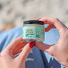 Person holding a small jar of **Bestie Brightening Bundle** labeled "Take us with you" with a blurred background, perfect for your oral care routine by **FRSHN UP**.