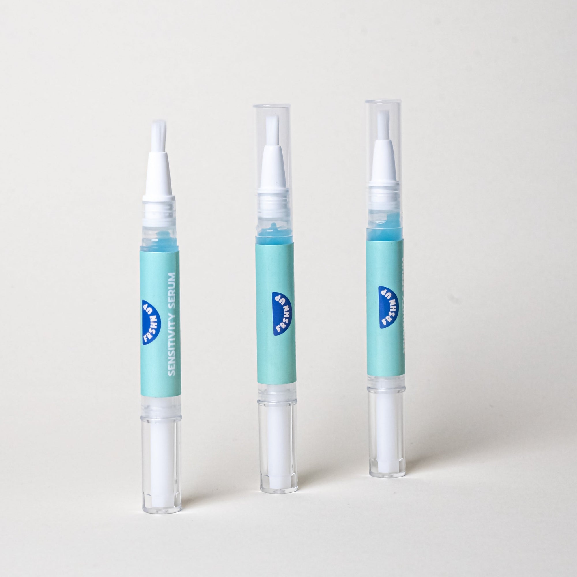 Three Sensitivity Serum by FRSHN UP blue and white bottles on a white surface, ideal for post-whitening treatment.