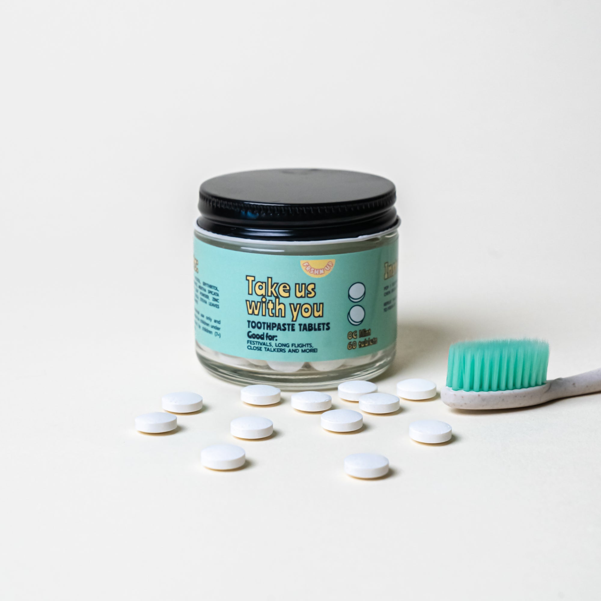 Description: A jar of FRSHN UP Toothpaste Tabs and a toothbrush for sensitive teeth on a white surface.